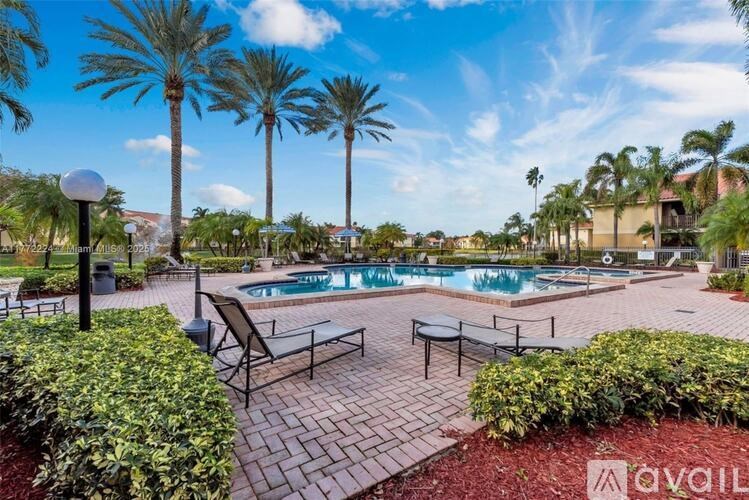 A pool surrounded by palm trees and a patio area with chairs.