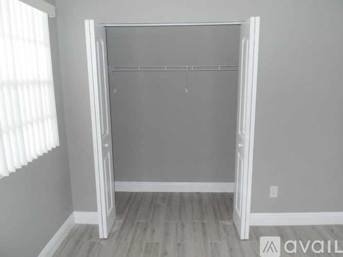 A white closet with a wooden floor and a white door.