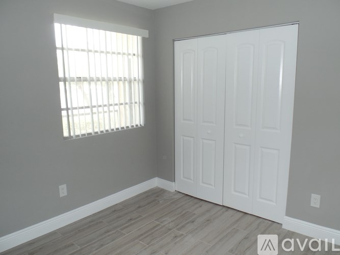 A room with a white door and a window with blinds.
