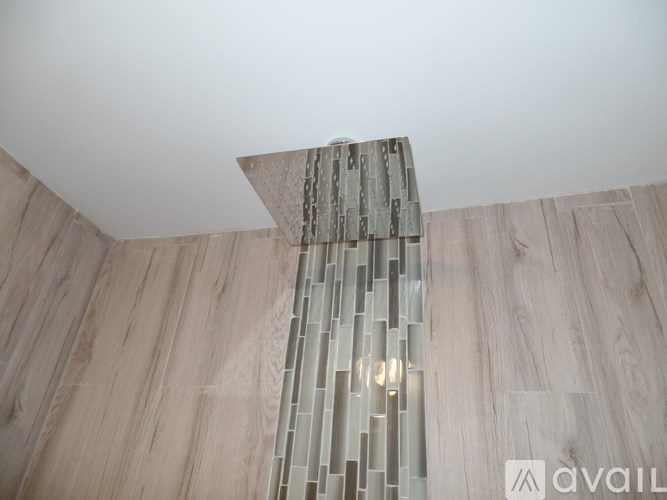 A modern chandelier hangs from a ceiling with wooden flooring below.