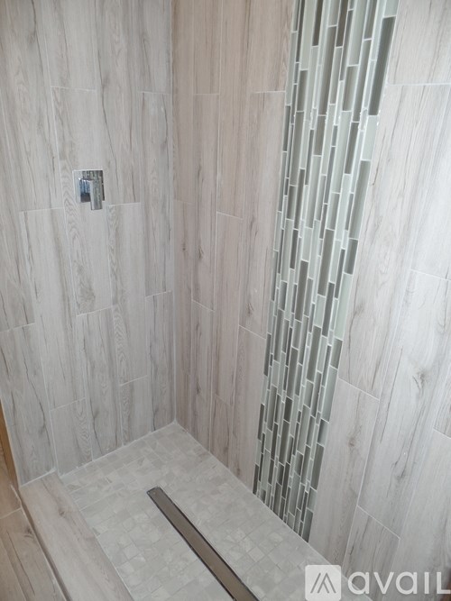 A bathroom with a tiled shower and a wooden floor.