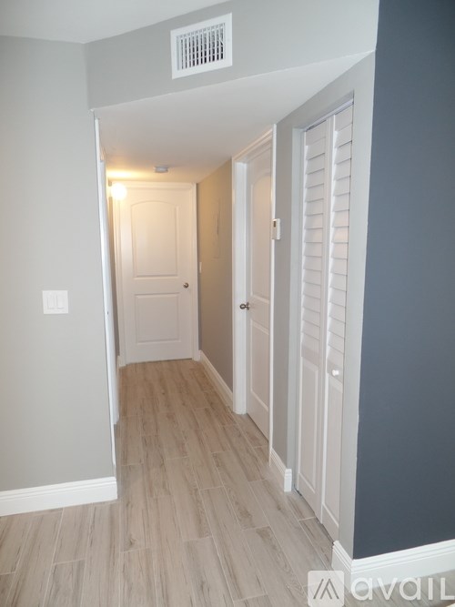 A hallway with a white door and a light switch on the wall.