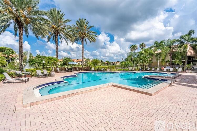 A large outdoor swimming pool surrounded by palm trees.