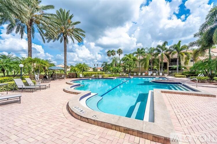 A pool surrounded by palm trees and lounge chairs.