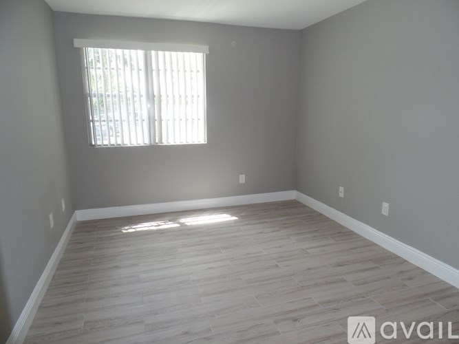 A room with wooden flooring and a window letting in sunlight.