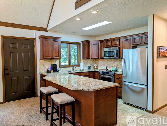 A kitchen with a refrigerator, stove, and bar stools.