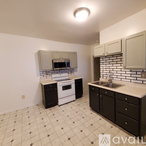 A kitchen with black and white tiles and white appliances.