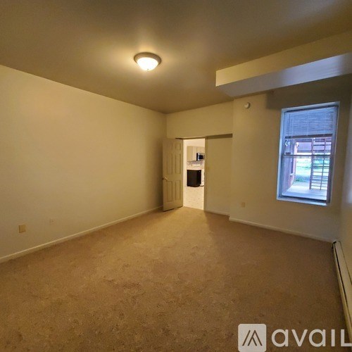 A room with beige carpeting and a window showing daylight.