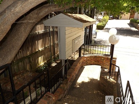 A small wooden structure with a black railing and a brick wall.