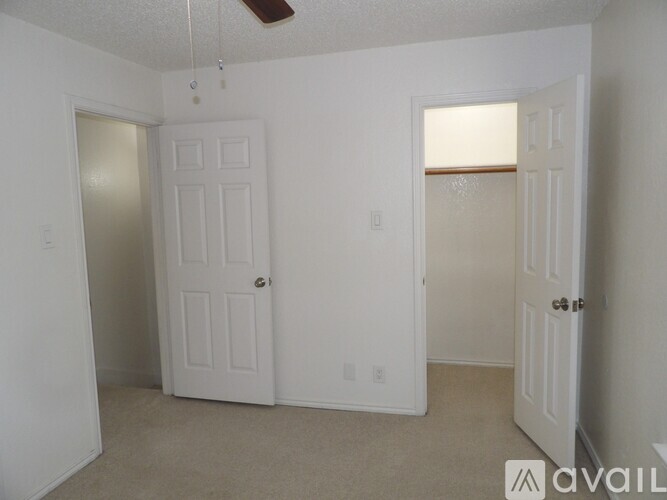 A room with two white doors and a ceiling fan.