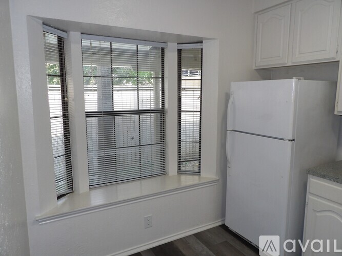 A kitchen with a white fridge and a window with blinds.