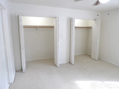 Two open closets with white walls and carpet.