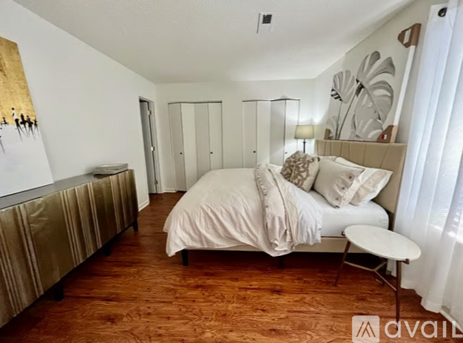 A bedroom with a bed, a chair, and a painting on the wall.