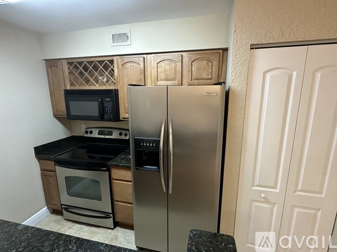 A kitchen with a stainless steel refrigerator and wooden cabinets.