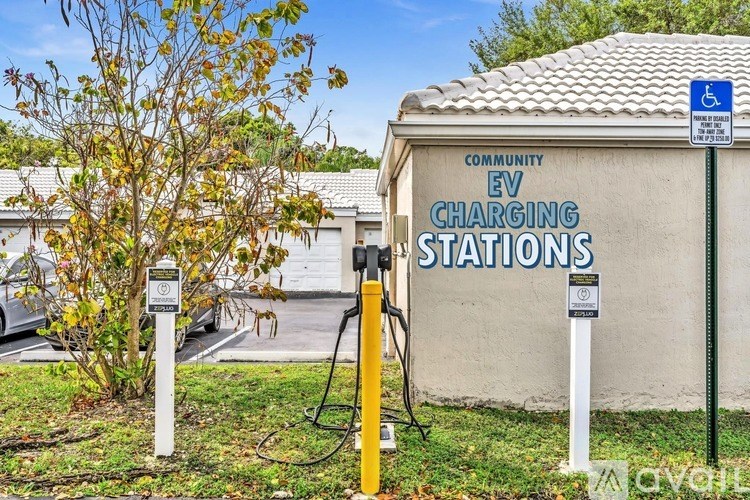 A wall with a sign that says "EV CHARGING STATIONS" in front of a tree.