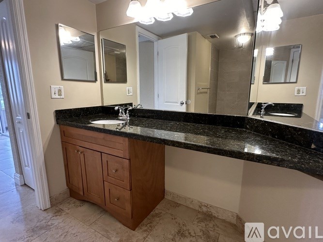 A bathroom vanity with a black countertop and a wooden cabinet.