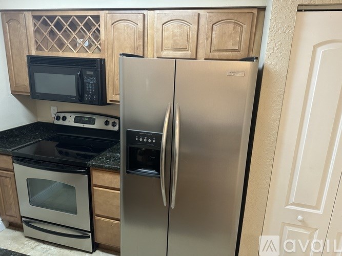 A kitchen with a stainless steel refrigerator and black appliances.