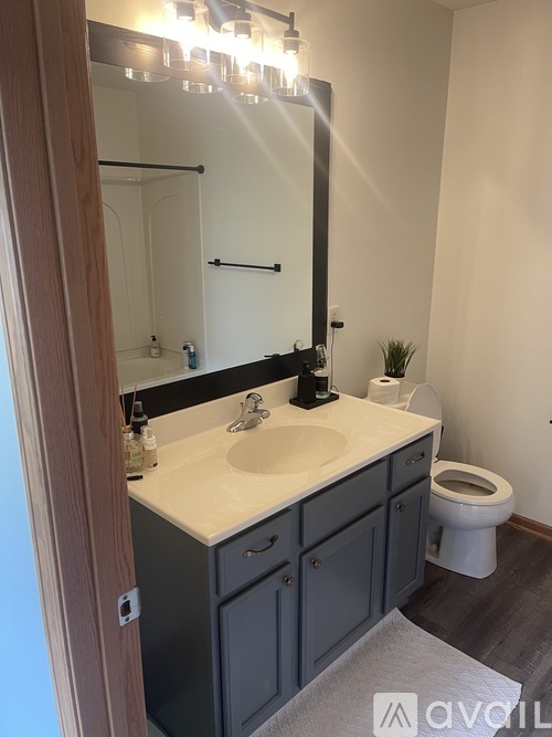 A bathroom with a sink, toilet, and mirror.