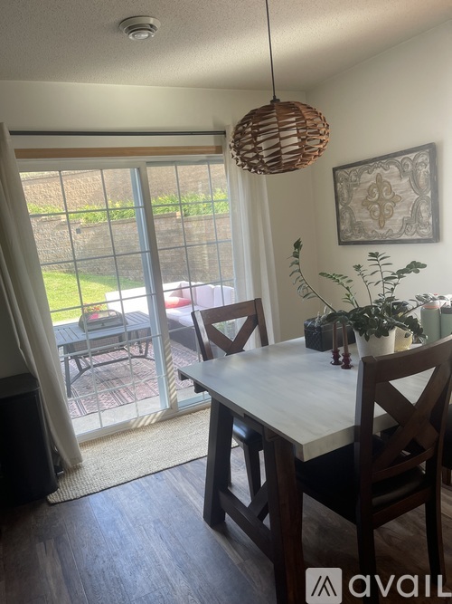 A dining room with a table and chairs and a hanging light fixture.