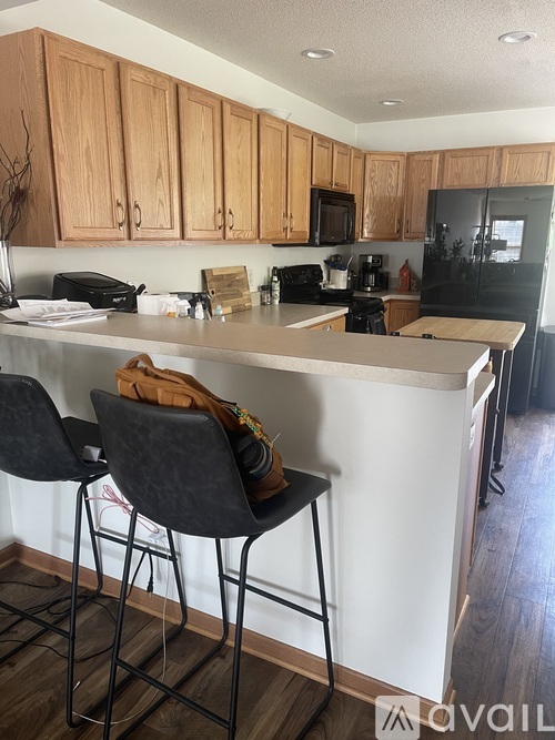 A kitchen with a white counter top and black barstools.