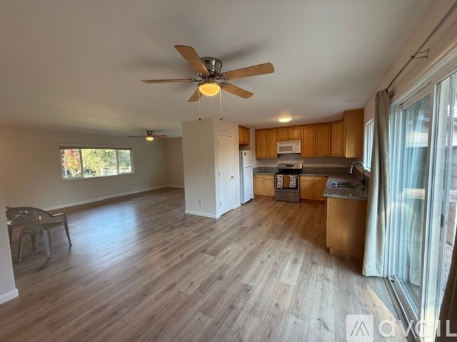 A spacious living room with a ceiling fan and hardwood flooring.