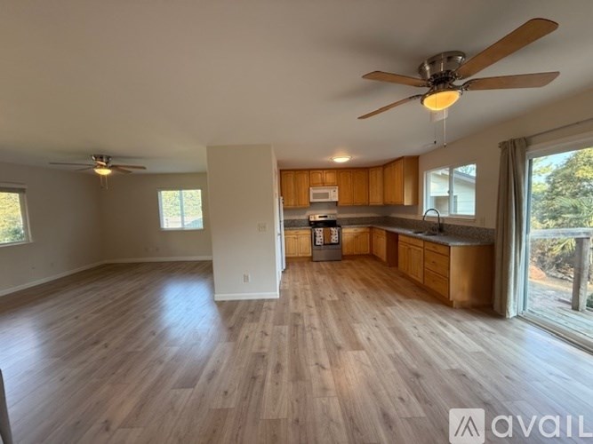 A spacious living room with wooden flooring and a ceiling fan.