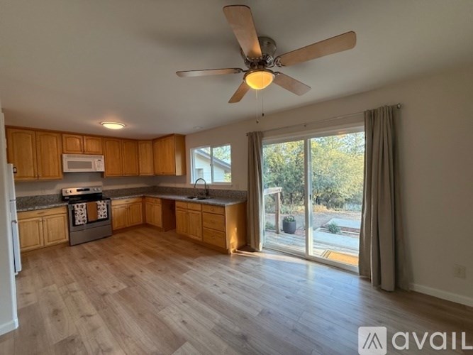 A spacious kitchen with wooden cabinets and a fan on the ceiling.