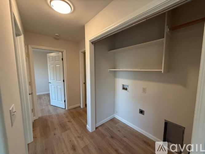 A room with a white door and a white wall with a shelf above it.