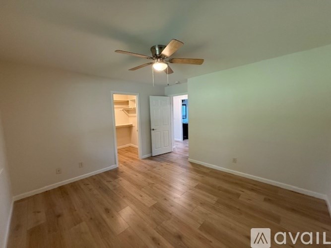 A room with a ceiling fan and wooden flooring.