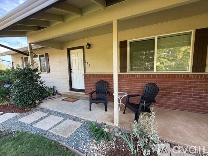 A house with a white door and two chairs on the porch.