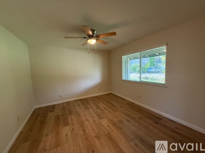 A room with a ceiling fan and wooden flooring.