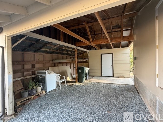 A garage with a gravel floor and a white refrigerator.