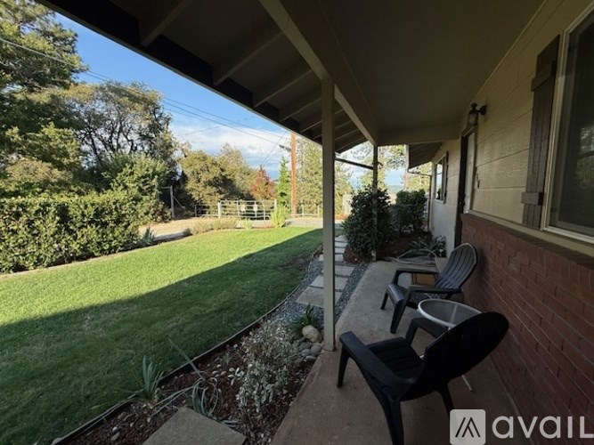 A patio with a table and chairs overlooks a green lawn.