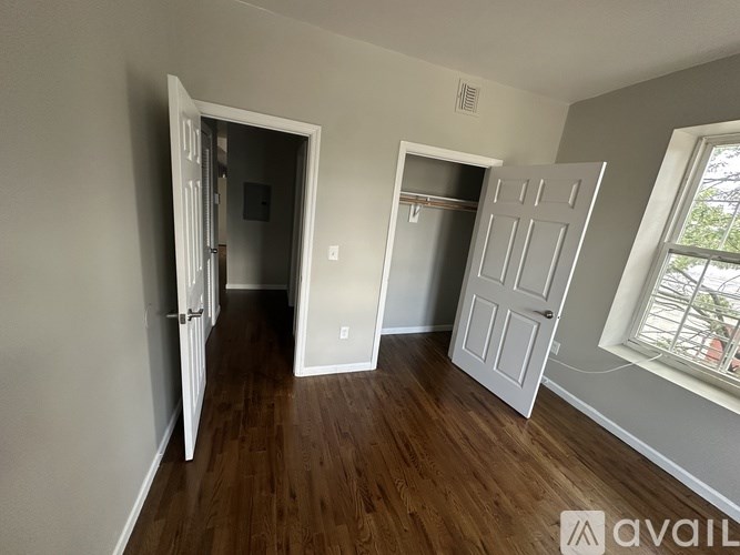A room with a white door and a window with a view of trees.