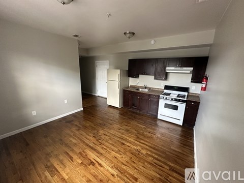A kitchen with white appliances and wooden floors.