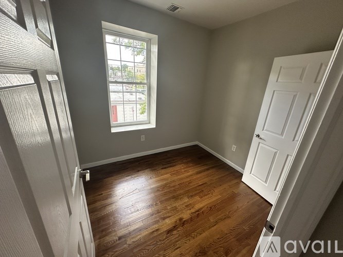 A room with wooden flooring and a window letting in light.