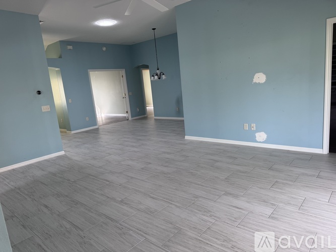 A spacious room with light blue walls and grey flooring.