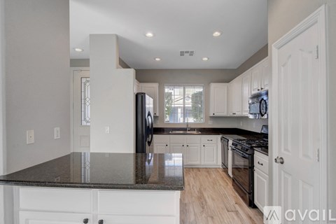 A kitchen with a black granite countertop and white cabinets.