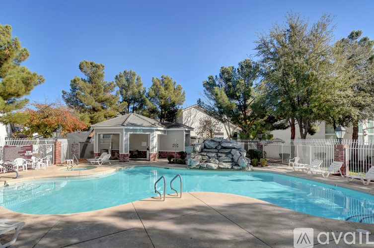 A pool surrounded by trees and a house in the background.