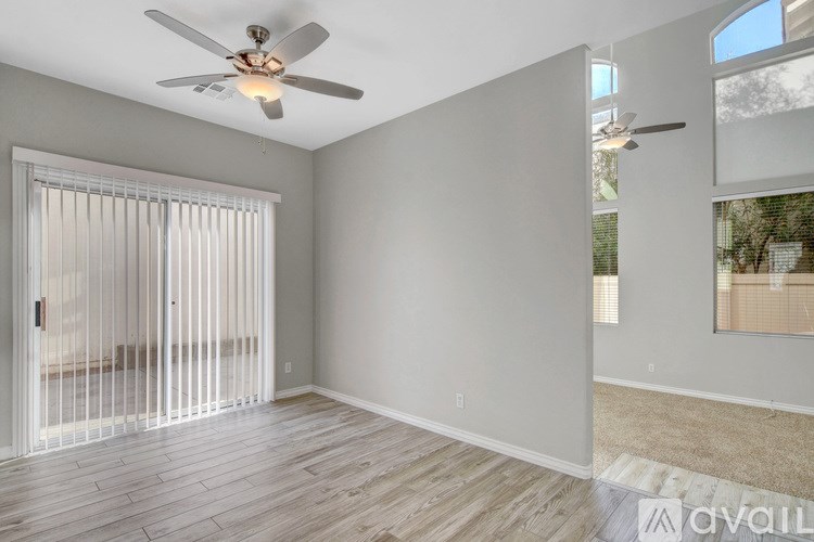 A room with a ceiling fan and sliding glass doors.
