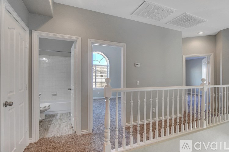 A well-lit room with a carpeted floor and a white railing.