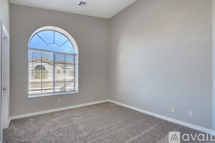 A room with a large arched window and carpeted floor.