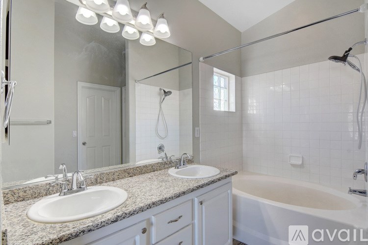A bathroom with a large mirror, double sinks, and a bathtub.