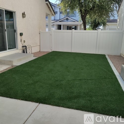 A backyard with a white fence and a green lawn.