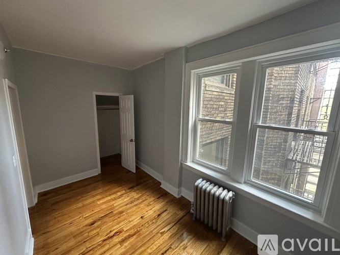 A room with wooden floors and a window showing a city view.
