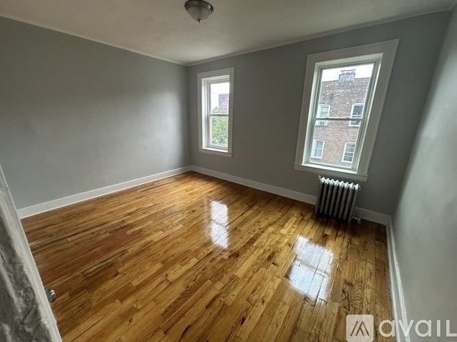 A room with wooden floors and two windows.