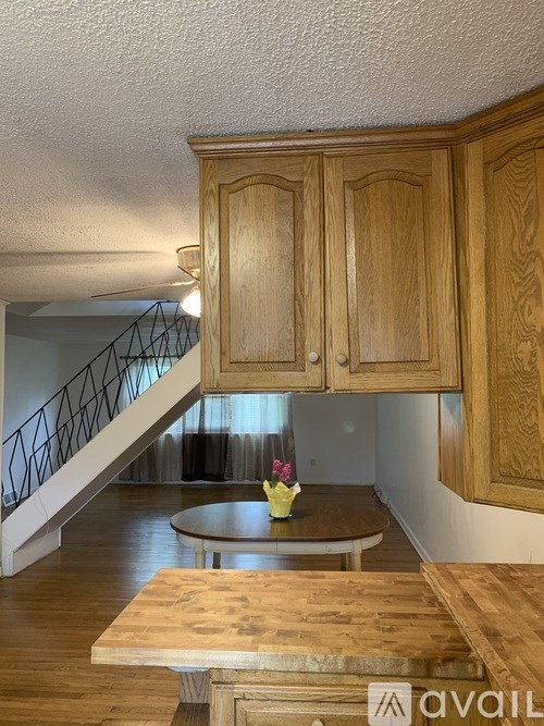 A wooden table with a vase of flowers on it in a room with wooden cabinets.
