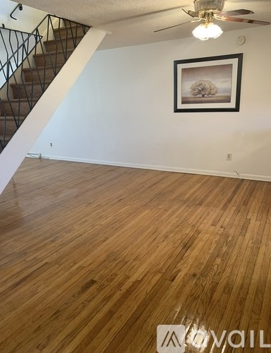 A room with wooden floors and a staircase with a metal railing.
