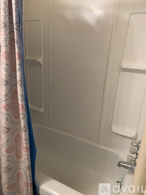 A bathroom with a white tub and a blue and pink shower curtain.