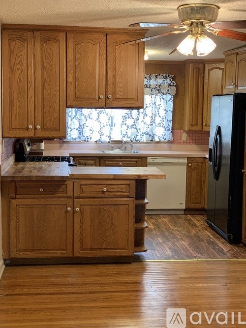 A kitchen with wooden cabinets and a black refrigerator.